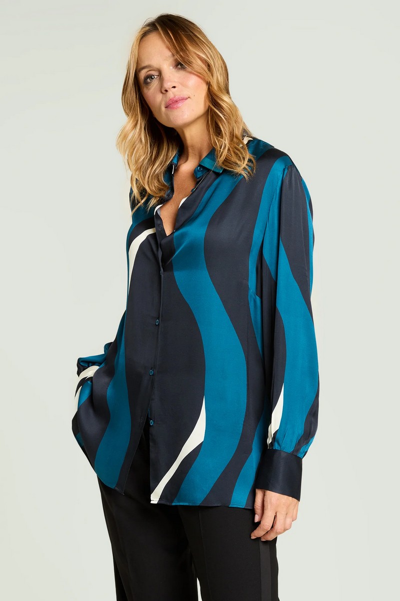 Μεταξένια αίσθηση και δυναμική εμφάνιση σε ένα πουκάμισο που ξεχωρίζει για το μοντέρνο κυματιστό του print. Η απαλότητα της βισκόζης συνδυάζεται με το κομψό φινίρισμα, δημιουργώντας ένα ρούχο που αποπνέει θηλυκότητα και στυλ. Σύνθεση 100% Βισκόζη Λεπτομέρειες Σχεδίασης • Κλασικός γιακάς • Μακριά μανίκια με μανσέτες • Μπροστινό κλείσιμο με κουμπιά • Κυματιστό μοτίβο σε αντίθεση • Ίσιο τελείωμα Ιδανικό για Εντυπωσιακές εμφανίσεις στο γραφείο ή σε βραδινές εξόδους με tailored παντελόνι ή μονόχρωμη φούστα.