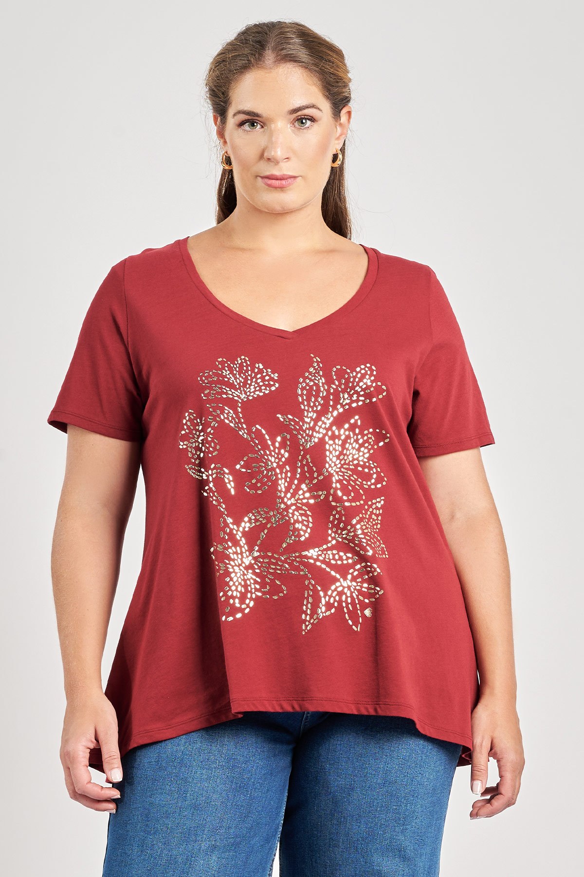 Βαμβακερό t-shirt με foil φλοράλ τύπωμα μπροστά. V λαιμόκοψη. Κοντά μανίκια. A-γραμμή. Κανονική εφαρμογή. Το μοντέλο έχει ύψος 180 εκ, στήθος 107, μέση 95, περιφέρεια 122 και φοράει το μέγεθος S