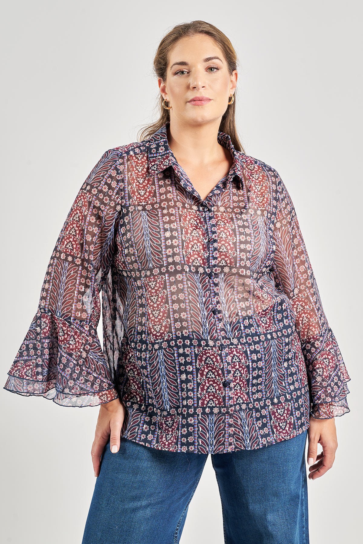 Πουκάμισο από αιθέριο ημιδιάφανο chiffon σε boho εμπριμέ με patchwork μοτίβο. Γιακάς πουκαμίσου και κούμπωμα με κουμπιά στην ίδια ύφανση κατά μήκος. Μακριά αέρινα μανίκια με βολάν στο τελείωμα. Το μοντέλο έχει ύψος 180 εκ, στήθος 107, μέση 95, περιφέρεια 122 και φοράει το μέγεθος S