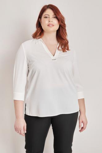Μονόχρωμη μπλούζα με V. Γιακάς πουκαμίσου και διακόσμηση στο V. Μανίκια 3/4 με κουμπί. Το μοντέλο έχει ύψος 180 εκ, στήθος 106, μέση 88, περιφέρεια 117 και φοράει το μέγεθος S